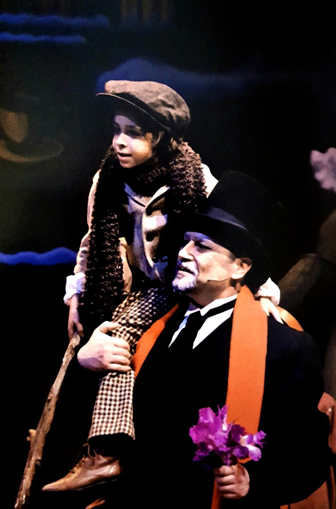 Philip Paul Kelly as "Ebenezer Scrooge" carrying "Tiny Tim" in " A Christmas Carol."